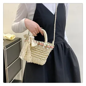 Detail of straw woven bucket bag with pink floral accents and lace bow decoration