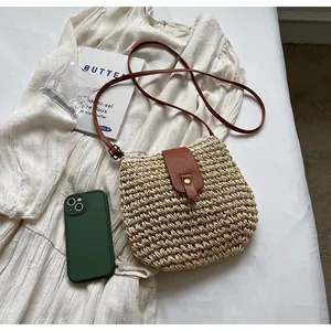 Détail macro du sac en paille tressée avec rabat en cuir et fermoir sur tissu blanc