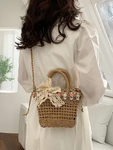 Straw woven crossbody bucket bag with lace bow and floral accents for beach vacations