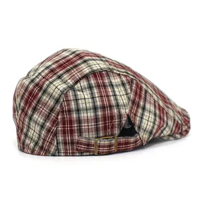 Close-up of multicolor plaid beret hat with adjustable bronze metal buckle and texture