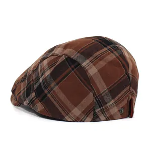 Close-up of vintage brown plaid flat cap featuring side buckle and textured fabric