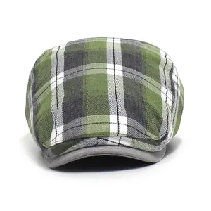 Detail of green plaid flat cap featuring woven check pattern and grey brim binding finish