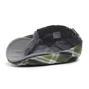 Detail of plaid beret hat showing grey lining, washing label and metal buckle adjustment