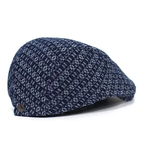 Detail of navy blue jacquard denim flat cap featuring metal buckle and textured fabric
