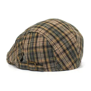 Detail view of the vintage plaid flat cap featuring an adjustable bronze metal buckle