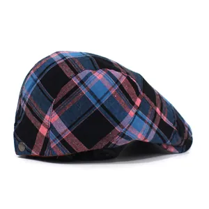 Detail of blue and pink plaid fabric texture and bronze buckle on newsboy cap