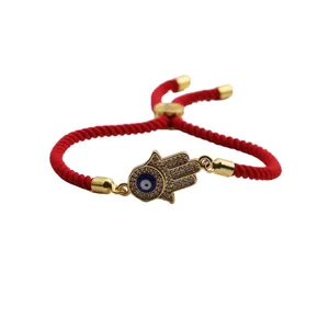 Detail of red braided string bracelet with Hamsa Hand and Evil Eye zircon pendant