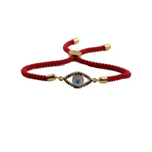 Detail of red braided evil eye bracelet with colorful zircons and adjustable gold sliding clasp