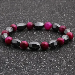 Detail of pink cat-eye stone beads and faceted dark grey hematite beads on a black background
