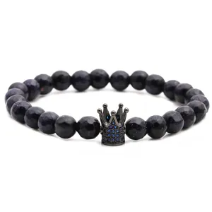 Dettaglio delle perle in pasta di vetro blu sfaccettate e ciondolo a corona nera su bracciale