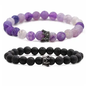 Macro detail of purple crackle stone and black volcanic rock bracelets with crown charms
