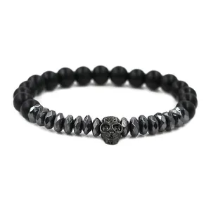 Close-up of matte black beads and a metallic skull charm on a gothic style men's bracelet