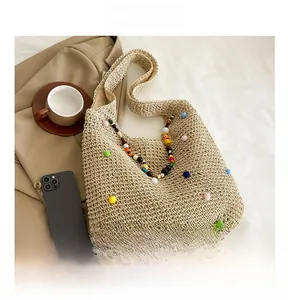 Close-up of handmade straw tote with colorful pom-poms and beaded handle detail