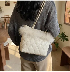 Detail showing plush feather trim and quilted texture on a beige chain crossbody bag