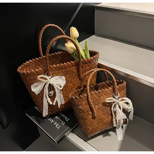 Detail of dark brown woven tote bags featuring pearl lace bows and heart charms