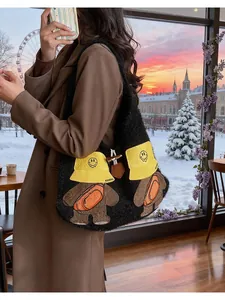 Detail of black fuzzy knit tote bag featuring cute cartoon bear patches and smiley hat