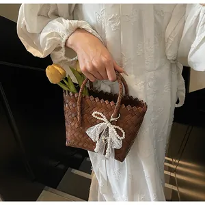 Detail of dark brown woven tote with lace, pearls and metal heart charm accessories