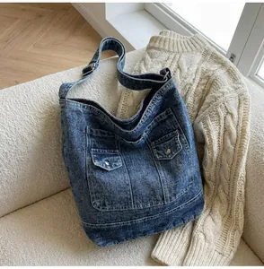 Détail du sac fourre-tout en denim vintage avec poches cargo et texture délavée sur canapé