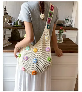 Dettaglio della borsa in maglia traforata con fiori all'uncinetto e tracolla larga retro