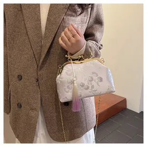 Detail of silk jacquard shell bag with vintage metal clasp and long gradient tassel