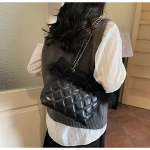 Detail of black quilted leather handbag featuring decorative faux fur trim and chain strap
