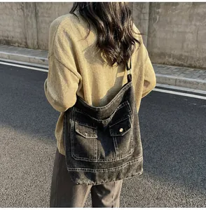 Détail du sac bandoulière en denim gris foncé avec poches cargo et surpiqûres blanches