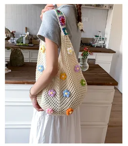 Dettaglio della borsa tote beige in maglia con fiori colorati lavorati all'uncinetto