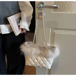Detail of white quilted handbag with feather trim and gold chain handle on door