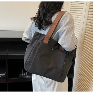 Detail view of large canvas tote bag with brown straps and functional side pockets