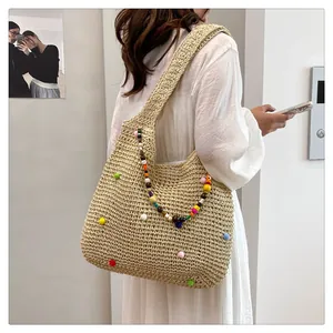 Close-up of handmade straw tote with colorful ethnic beads and woven shoulder strap