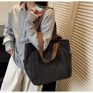 Close-up of black canvas tote bag showing side pocket and front magnetic flap pocket