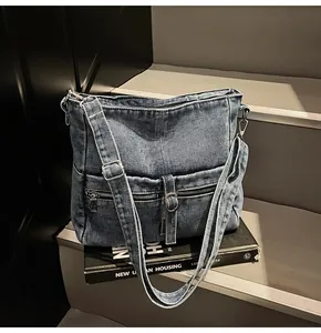 Detail of vintage blue denim hobo bag featuring silver hardware and wide shoulder strap