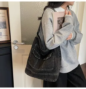 Détail du sac fourre-tout en denim noir délavé avec doubles poches cargo et coutures blanches