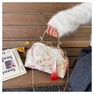 Detailed macro view of vintage kiss-lock bag with floral embroidery and golden tassel