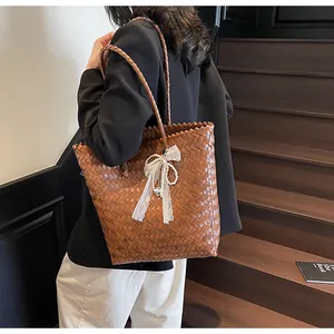 Detail of woven straw tote bag featuring elegant lace pearl bow charm and brown texture