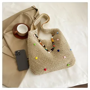 Detailed weave texture of the straw tote bag with colorful pom-poms and beaded straps