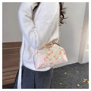 Detail of pink silk shell bag with red persimmon embroidery and gold chain strap
