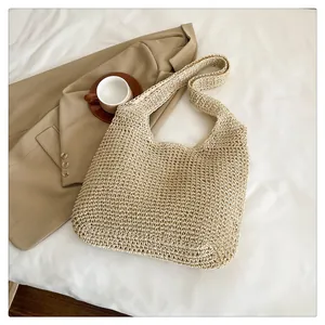 Detailed grid weave texture of a beige straw tote bag with wide shoulder strap