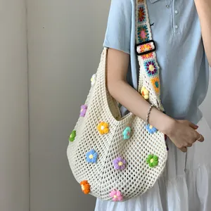 Dettaglio dei fiori all'uncinetto e della tracolla larga sulla borsa tote color crema