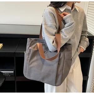 Detail of gray canvas tote bag featuring multi-pocket design and brown woven straps