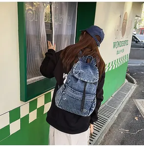 Outdoor shot showing back view of vintage washed denim backpack with drawstring closure