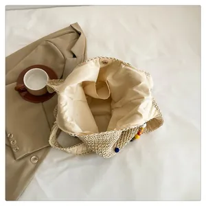 Detail of straw tote bag interior with magnetic closure and colorful bead charm decoration