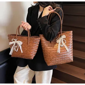 Comparison of two sizes of brown woven bags with white lace bow and pearl charms