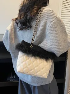 Quilted off-white chain bag with black faux fur trim shown on a model in knitwear