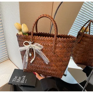 Detail of woven straw tote bag with white lace trim and pearl bow charm accessory