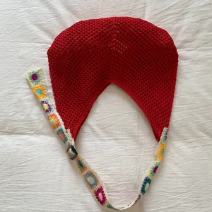 Dettaglio borsa a uncinetto rossa con tracolla floreale colorata su lino bianco