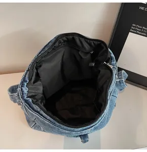 Macro view showing the spacious interior of a blue denim crossbody bag with black lining