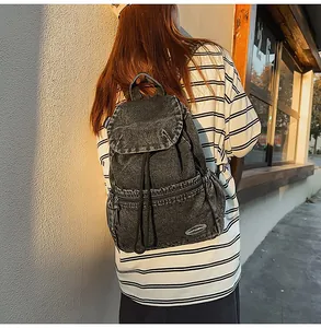 Detail of vintage washed black denim backpack with flap closure and drawstring design