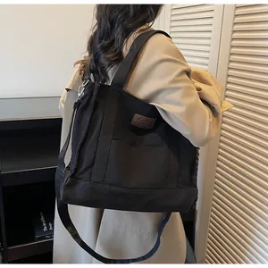 Detail of black canvas tote bag showing high-density material and leather patch