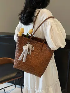 Brown woven tote bag with pearl and lace charm shown on model in a white dress